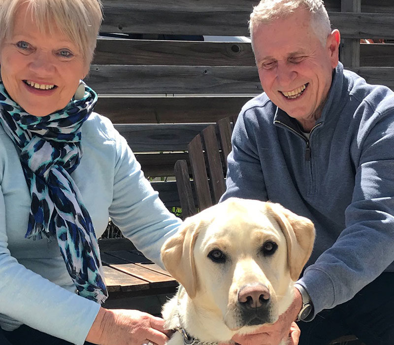 a smiling woman and man with a dog