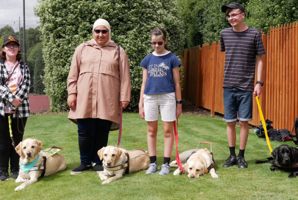 four young people standing next to Guide Dogs