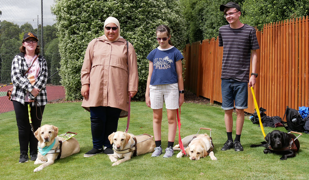 four young people standing next to Guide Dogs