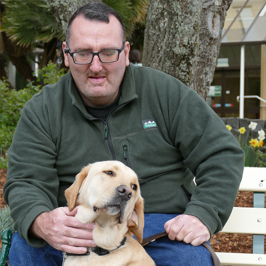 a man sitting behind his guide dog