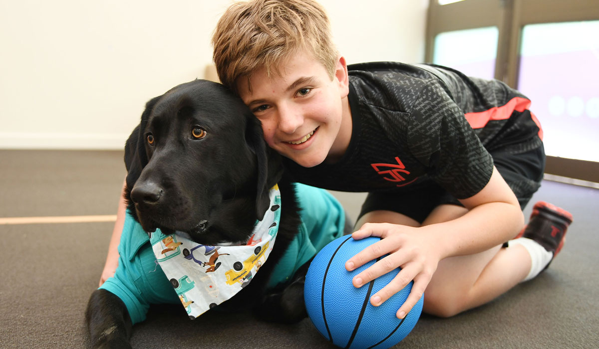 smiling young boy next to a dog in at shirt