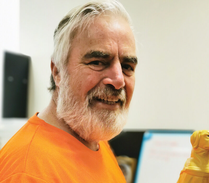 man smiling at camera holding mini collection dog