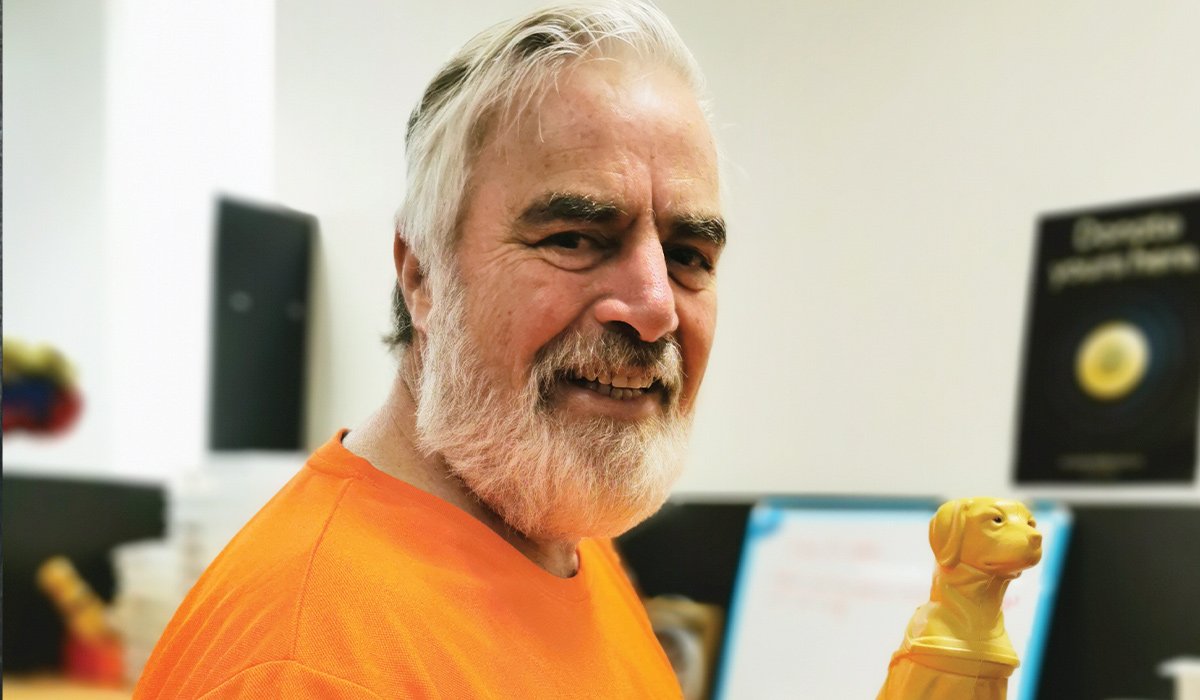 man smiling at camera holding mini collection dog