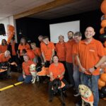 A large group of people in orange shirts stand for a group photo